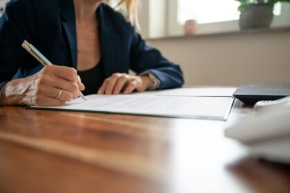 Businesswoman sitting at her office desk signing a contract