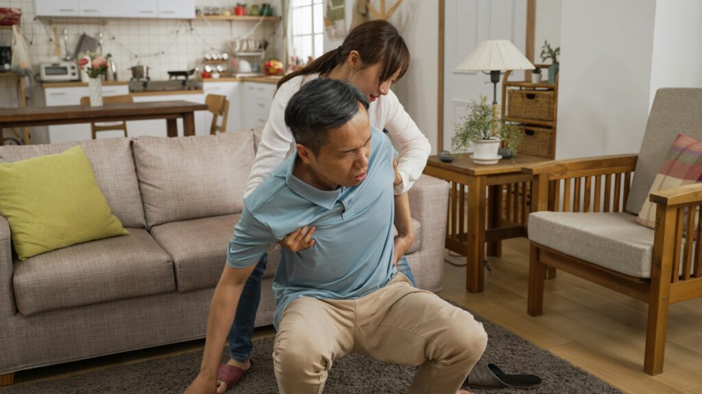 woman helps grandfather sit and rest after fall