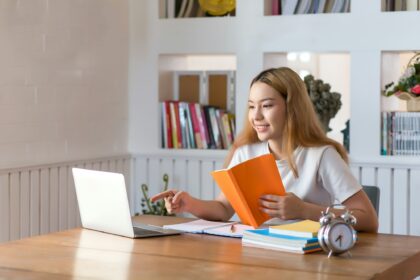 Young woman student working on laptop sitting in library at home