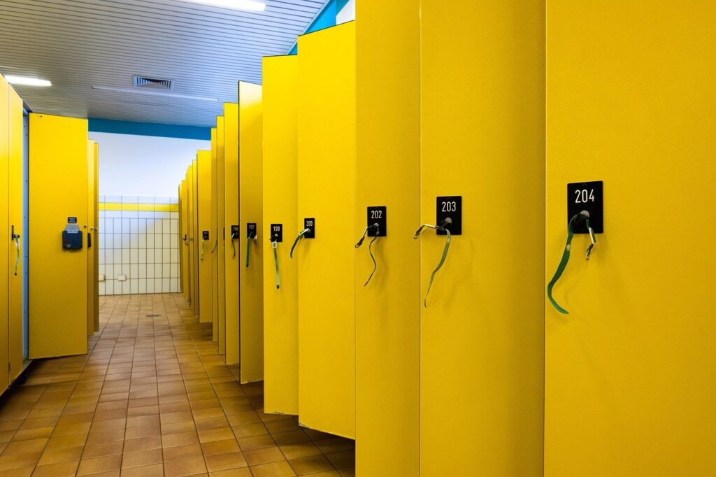 Bright yellow dressing room stalls with numbered doors and hanging cables in a modern retail facility