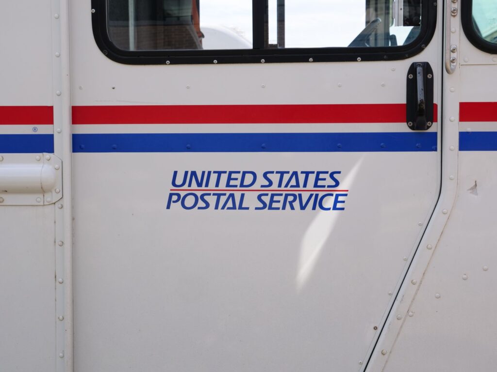 Side panel view of a United States Postal Service mail truck emphasizing its logo.