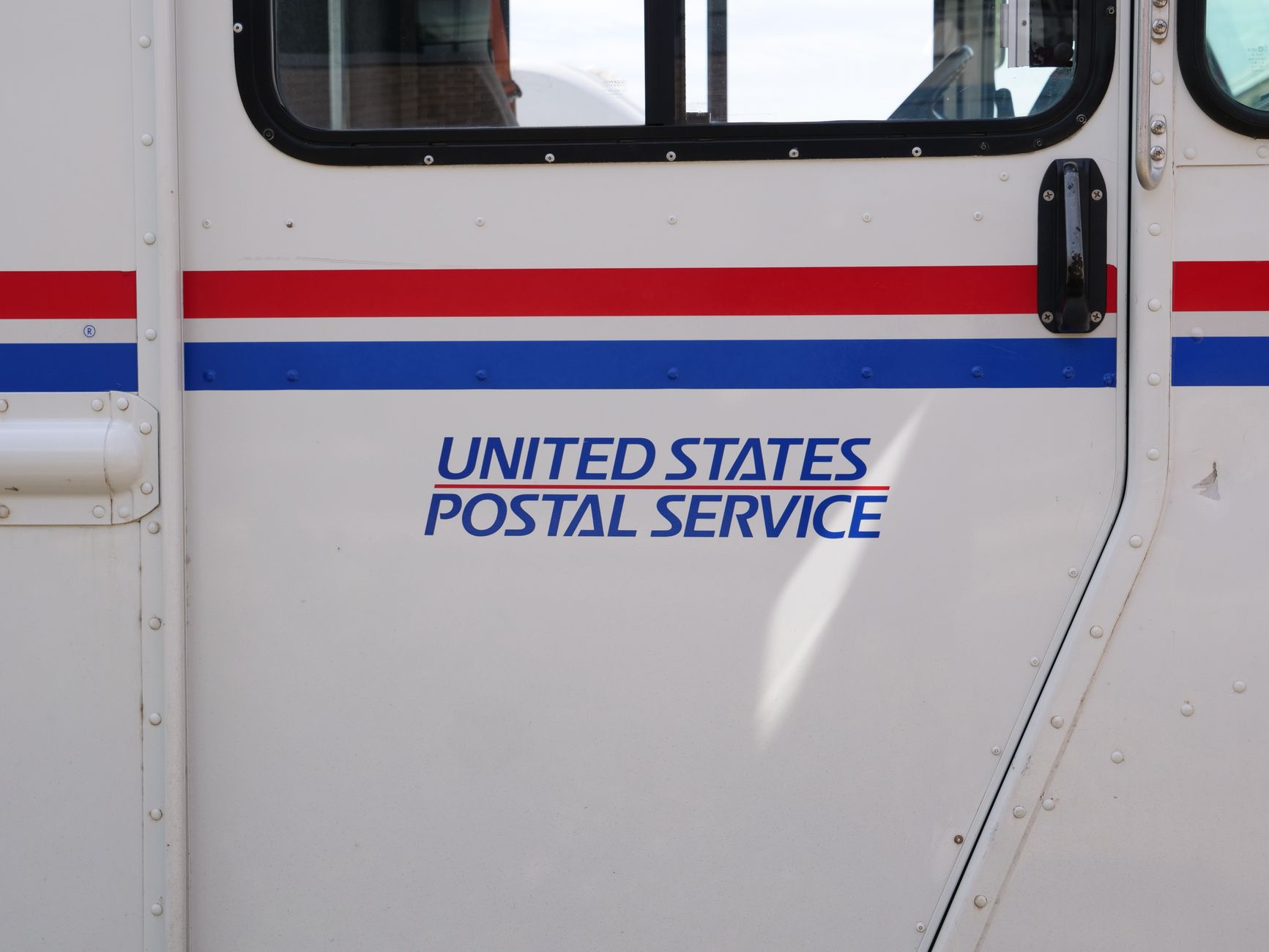Side panel view of a United States Postal Service mail truck emphasizing its logo.