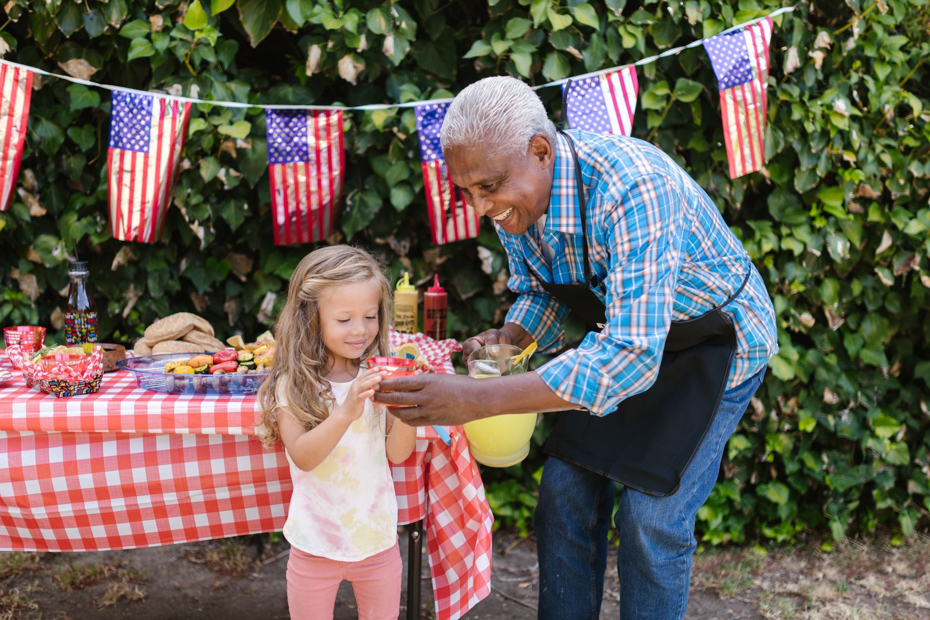 An outdoor family picnic with American flag decor and food, showcasing a joyful celebration.
