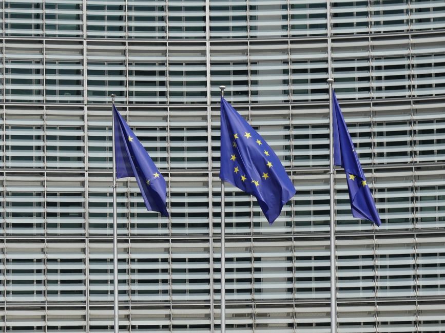 Three European Union flags waving outside the Berlaymont building in Brussels, Belgium.