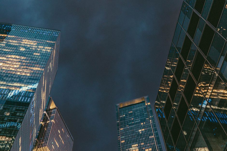 Low-angle shot of illuminated skyscrapers reflecting lights against a dark evening sky in Moscow.