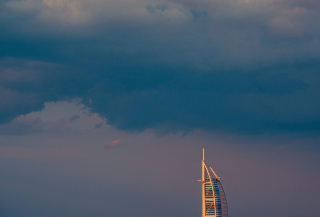 Scenic view of Burj Al Arab at sunset with dramatic cloud cover in Dubai, UAE.