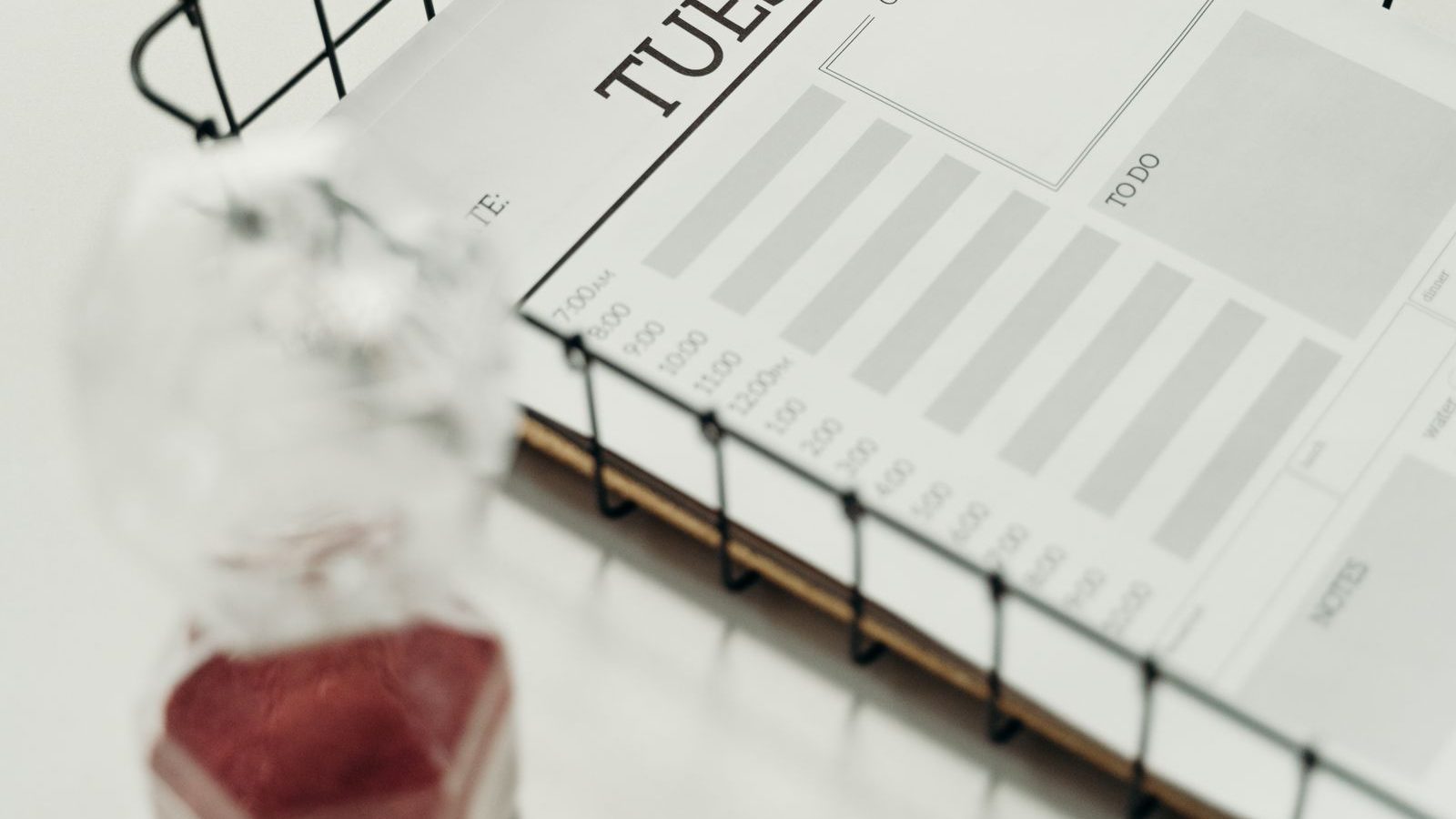 Hourglass beside a daily planner with hourly time slots, representing time records for AI-assisted legal work
