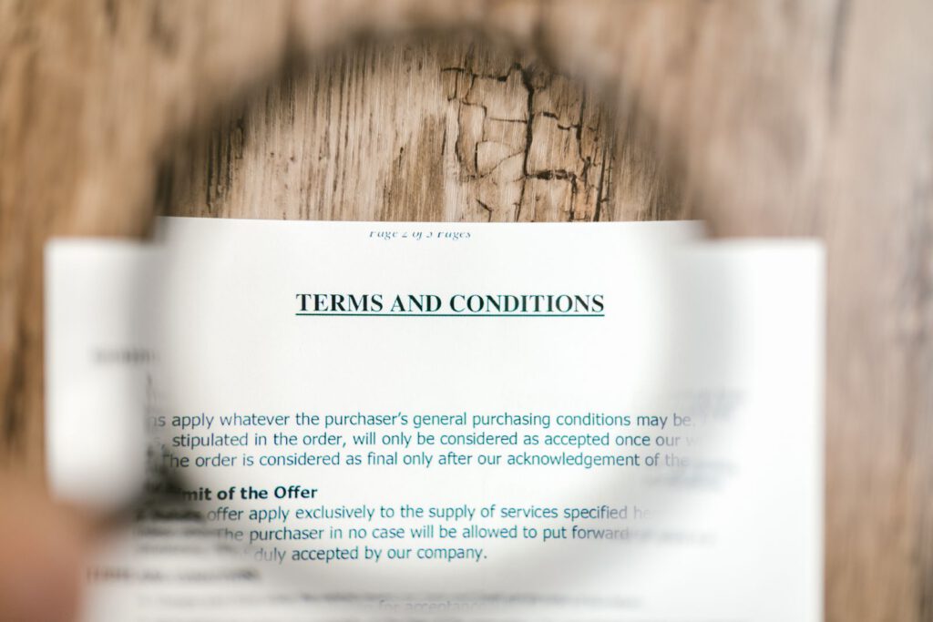 Magnifying glass over a printed terms and conditions page lying on a wooden table