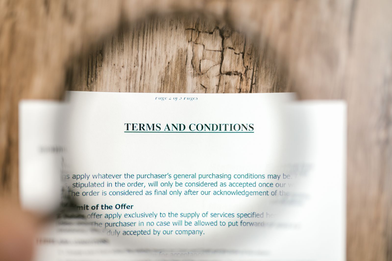 Magnifying glass over a printed terms and conditions page lying on a wooden table
