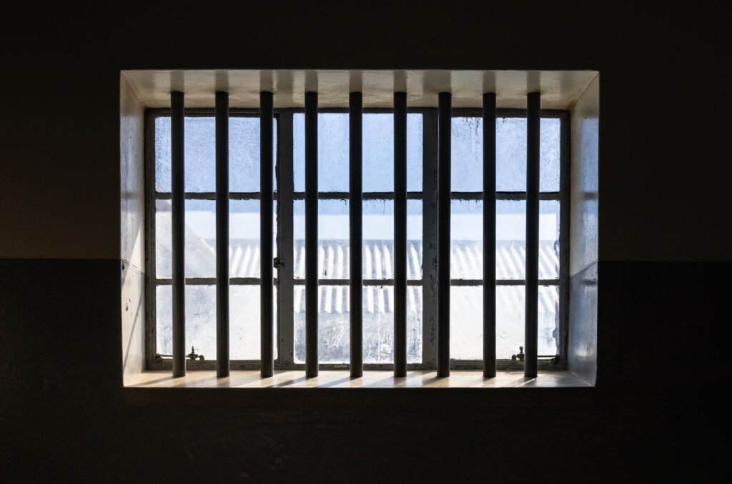 Sunlight through the barred window of an empty prison cell, representing detention and habeas corpus