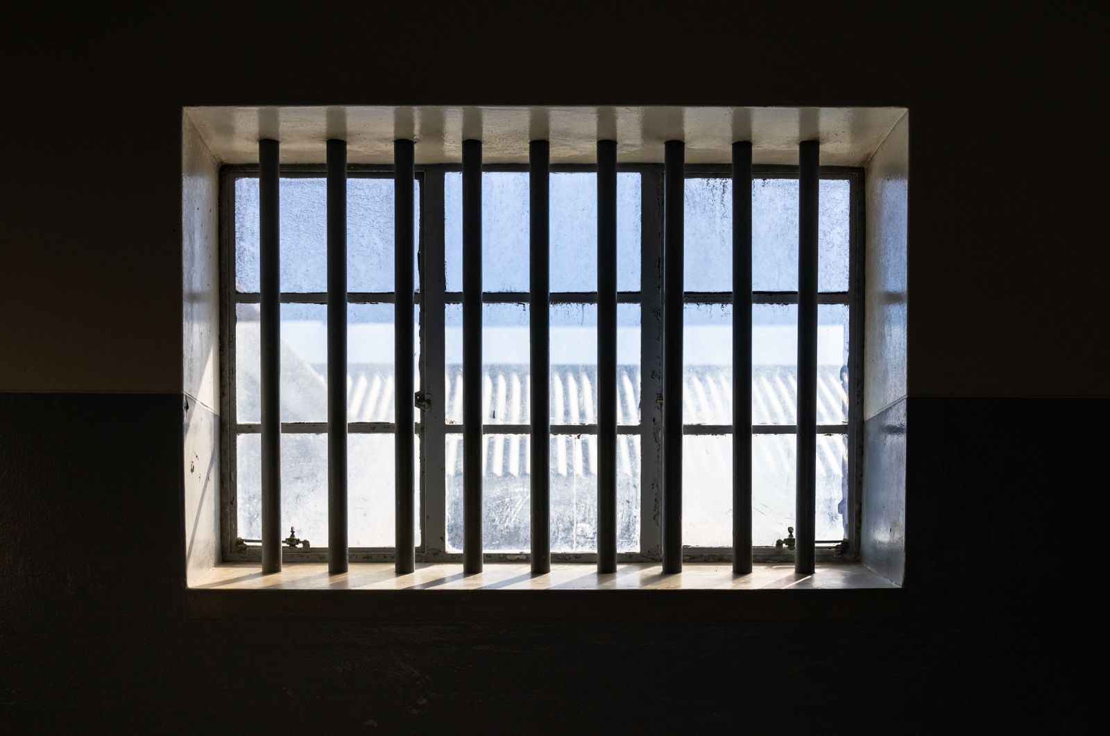 Sunlight through the barred window of an empty prison cell, representing detention and habeas corpus