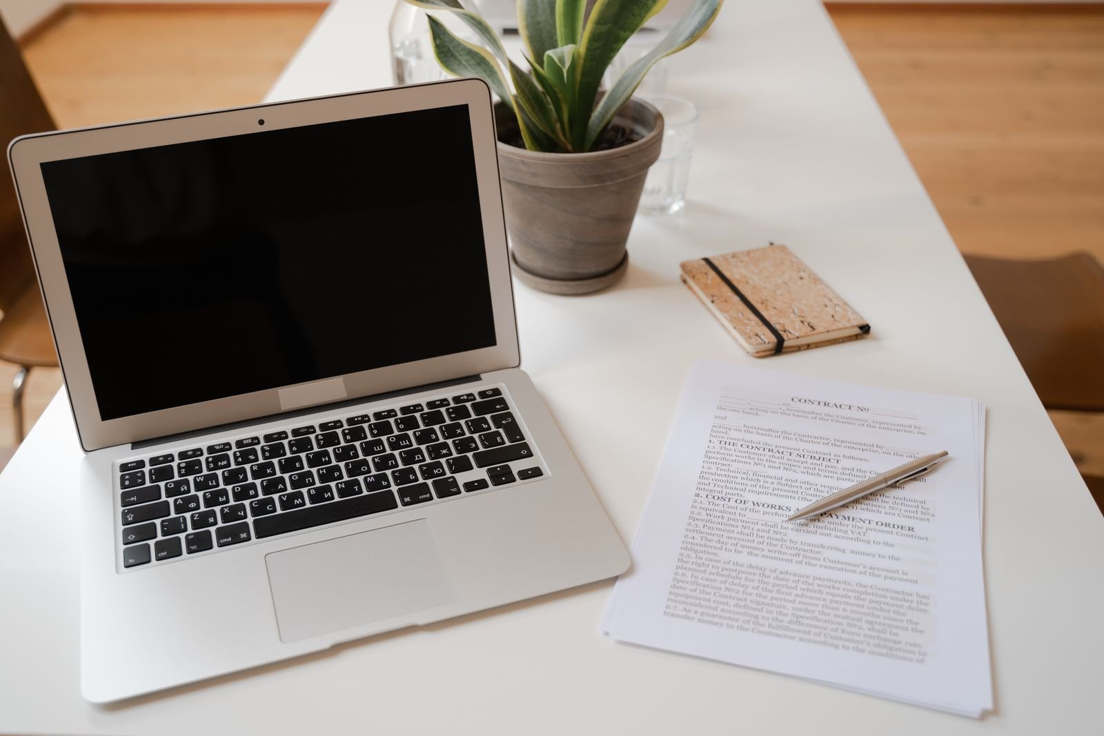 Laptop next to a printed contract and pen on a desk, representing AI document review