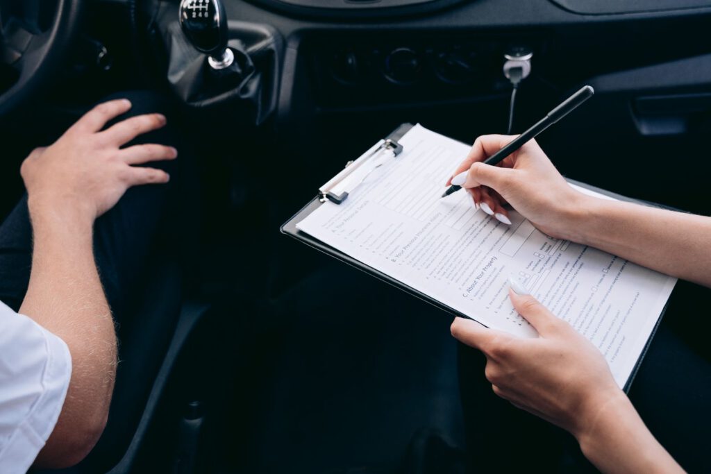 Person filling in an insurance claim form on a clipboard inside a car after an accident