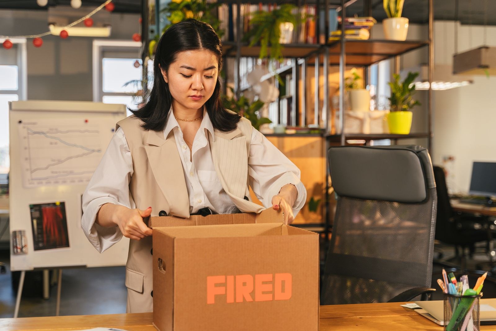 Office worker packing belongings into a cardboard box marked FIRED, illustrating a pretext termination