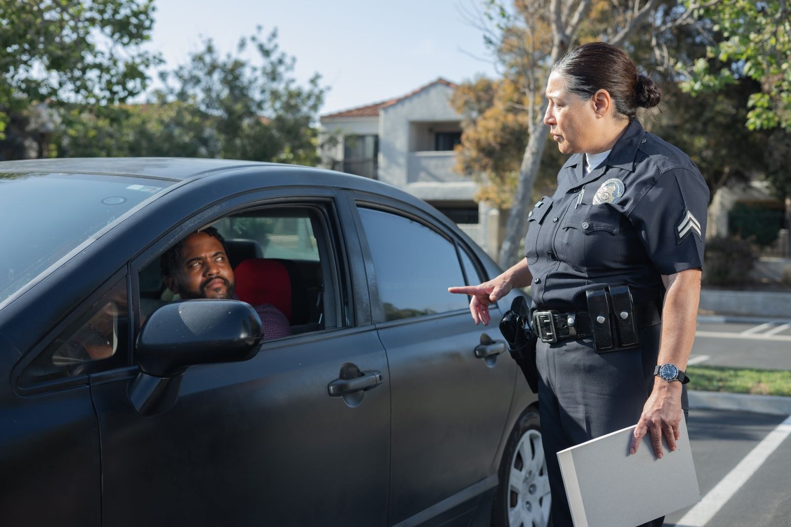 Police officer speaking to a seated driver through the car window during a roadside traffic stop
