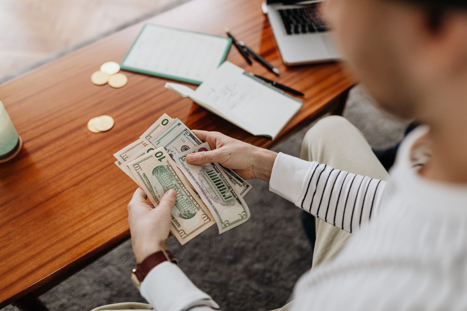 Person counting US dollar bills at a desk, representing money exchanged in bribery cases