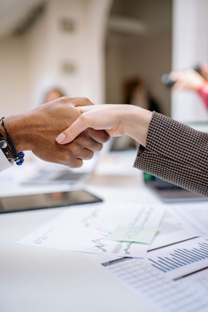 Two people shaking hands over business documents, illustrating a quid pro quo exchange