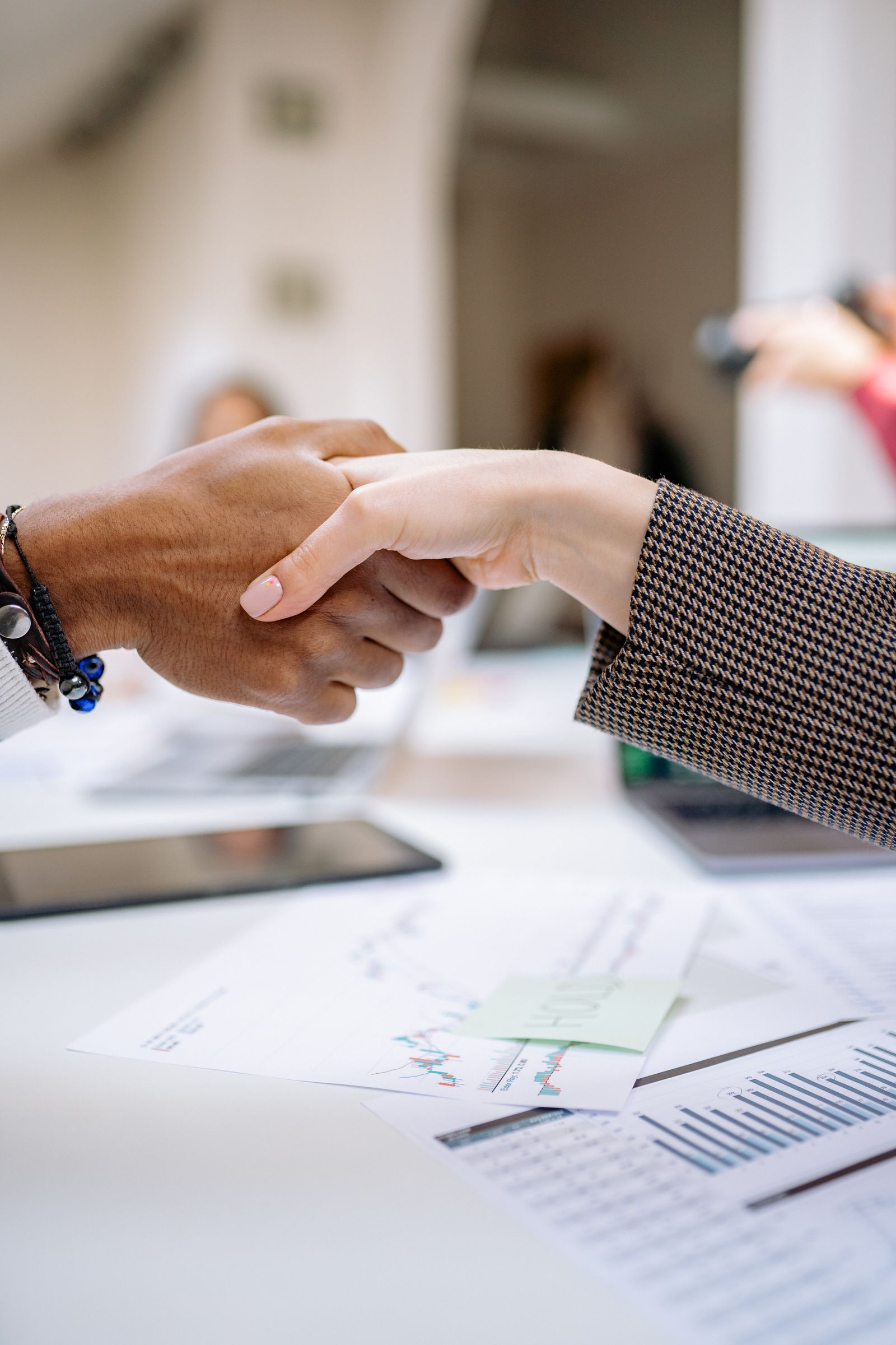 Two people shaking hands over business documents, illustrating a quid pro quo exchange