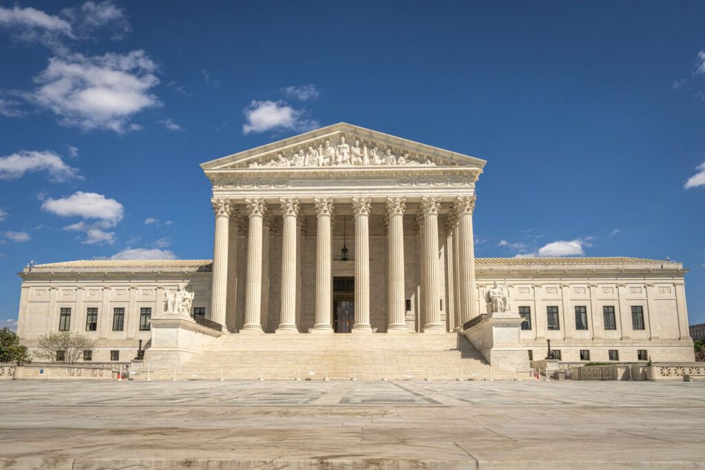 Front of the United States Supreme Court building in Washington, D.C. with its columns and pediment under a blue sky