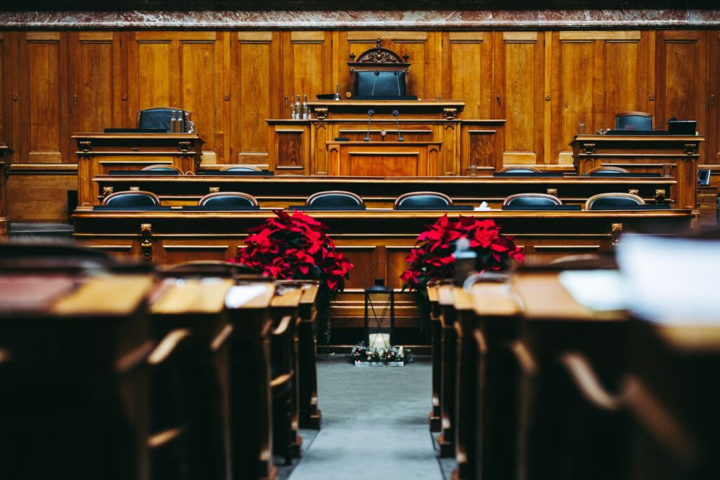 Wood-panelled courtroom in Bern with rows of empty seats facing the raised judges' bench