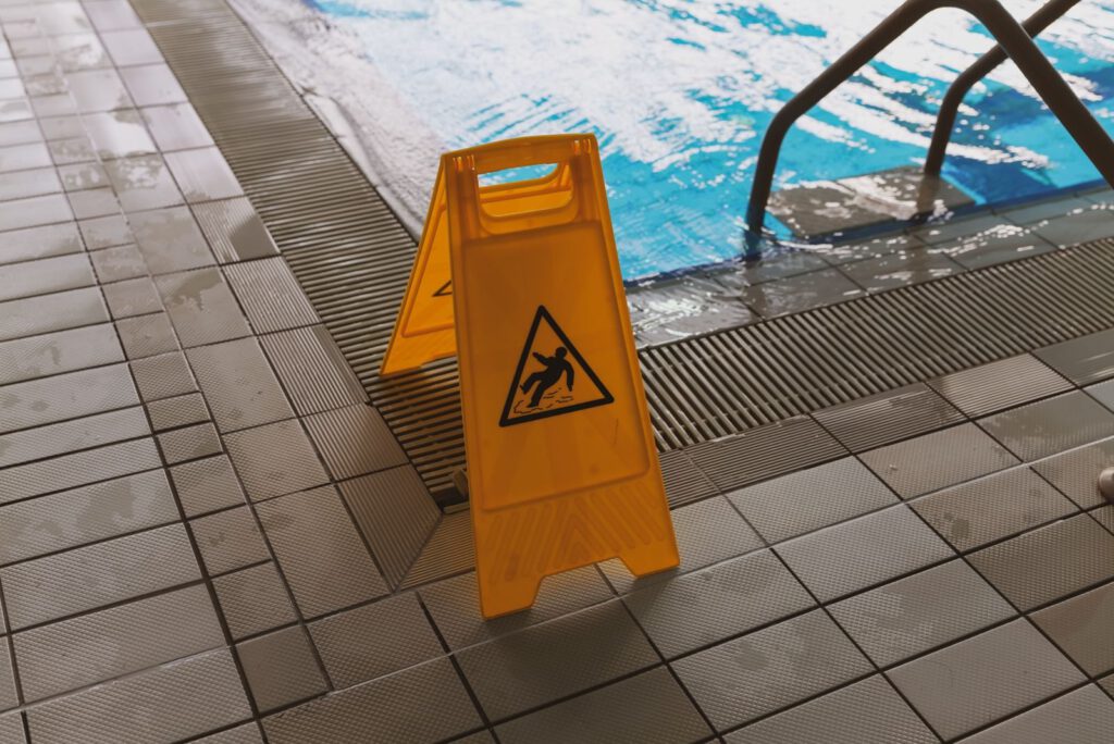 Yellow wet floor warning sign beside a swimming pool, a common setting for negligence and tort claims