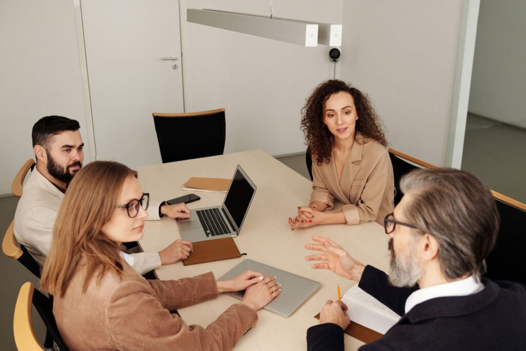 Four professionals in discussion around a conference table with laptops, similar to an arbitration hearing